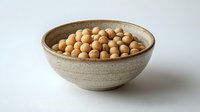 Raw soybeans in rustic ceramic bowl on white background, natural protein source, healthy legumes for cooking and plant-based nutrition.
