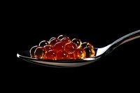 Red caviar pearls on silver spoon against black background for gourmet food photography and luxury dining concepts.