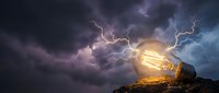 Giant glowing lightbulb on rocky terrain with dramatic lightning storm and purple clouds creating surreal energy concept for innovation and creativity.