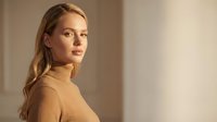 Young blonde Caucasian woman in beige turtleneck sweater looking over shoulder with soft natural lighting for fashion and lifestyle content.