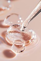 Transparent liquid drops forming heart shapes on pink background with water stream pouring, creating romantic macro photography effect with bokeh lights.