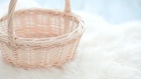 Empty wicker basket with handle on white fluffy surface for storage, picnic, gift presentation and home decor projects.