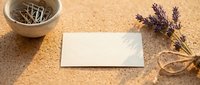 Blank white business card mockup on cork surface with lavender flowers and wooden bowl for branding design projects.
