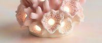 Soft pink coral-shaped ceramic candle holder glowing with warm light, elegant home decor accent with delicate floral texture on pastel background.