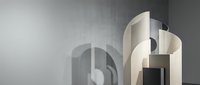 Modern minimalist architectural interior with curved geometric forms and soft lighting creating elegant shadows on textured wall surface.