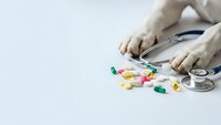 Medical stethoscope with colorful pills and capsules on white background. Healthcare concept for pharmaceutical treatment and medicine.