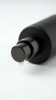 Black cosmetic pump dispenser with liquid droplet on white background, isolated product shot for skincare, beauty, and wellness packaging design.