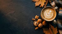 Overhead view of cappuccino with latte art surrounded by autumn leaves and walnuts on dark surface, perfect for fall beverage and seasonal cafe marketing.