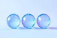 Three translucent blue crystal spheres with iridescent reflections arranged in row on light background, creating minimalist composition with soft purple highlights.