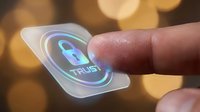 Hand holding translucent chip displaying trust security icon with glowing blue padlock symbol against warm bokeh background for cybersecurity concepts.