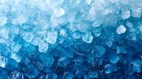Macro view of blue crystal ice cubes creating abstract cold pattern background. Frozen water fragments with light reflection showing natural texture.