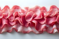 Delicate pink ruffled fabric trim creates elegant waves and folds against white background, showcasing intricate textile detail for fashion and craft design applications.