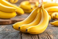 Fresh ripe yellow bananas on rustic wooden table, close-up view of tropical fruit for healthy eating and smoothie recipes.