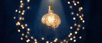 Vintage Edison bulb glowing warmly against dark blue background with golden bokeh lights creating magical atmosphere for creative projects and design work.