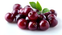 Fresh ripe cranberries with water drops and green leaves on white background, macro shot showing texture and natural shine of berries for food design.