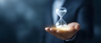 Glowing hourglass floating over open palm against dark background symbolizes time management, deadline pressure and business decision making concept.