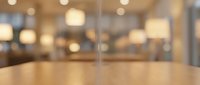 Wooden table surface in focus with blurred modern office interior, conference room, or corporate workspace background with warm lighting.