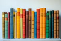 Row of vintage hardcover books arranged on wooden shelf, displaying colorful spines in yellow, red, green, and blue tones against light background. Library collection.