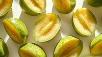 Fresh sliced green citrus fruits arranged in pattern on light background. Juicy lime halves with pulp texture showing natural organic produce.