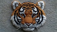 Close up portrait of majestic Bengal tiger head with detailed fur texture and striking blue eyes against gray background, artistic embroidered style design.