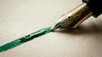 Fountain pen with green ink nib writing on white paper, suitable for stationery, writing, calligraphy, and office design projects.