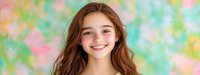Young Caucasian woman with long brown hair and bright genuine smile against soft pastel bokeh background. Natural beauty portrait expressing joy and happiness.