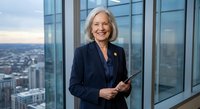 Confident senior Caucasian businesswoman with gray hair holding tablet in modern office with city skyline view through floor-to-ceiling windows.