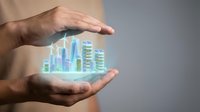 Hands holding glowing holographic cityscape with illuminated skyscrapers, representing urban development, smart city technology, and real estate investment opportunities.