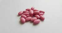 Pink oval tablets scattered on white background for pharmaceutical and healthcare design projects.