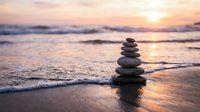Balanced stone stack on beach at sunset with gentle waves and golden light reflecting on wet sand creating peaceful meditation scene for wellness concepts.