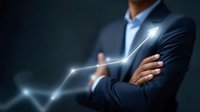 Professional Asian businessman with crossed arms standing next to glowing upward trend graph line on dark background, representing business growth and success.