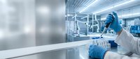 Scientist in protective gear conducting research in modern laboratory with test tubes and advanced equipment for pharmaceutical development.