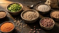 Assorted legumes and beans in wooden bowls on rustic table including lentils, chickpeas, kidney beans and edamame for healthy cooking and nutrition.