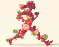 Creative arrangement of fresh berries and fruit slices forming letter A with strawberries, raspberries, blackberries and green leaves on light background.