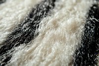 Extreme close-up macro photography of black and white fur texture showing intricate hair strands and fibers in soft focus, creating abstract natural pattern.