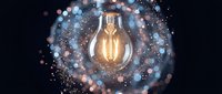 Glowing light bulb surrounded by sparkling particles and bokeh lights on dark background symbolizing innovation, creativity and bright ideas for business.