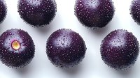 Fresh ripe acai berries with water drops on white background, macro shot of dark purple superfood fruit pattern for healthy eating and nutrition.
