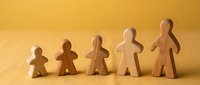 Five wooden figurines arranged by increasing size on yellow background, symbolizing growth, family, child development, or team progress.