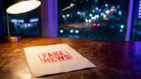 Fake news document on wooden desk with city lights background at night, media misinformation concept for journalism and digital literacy education.