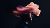 Surreal portrait of bearded man with pink smoke cloud emerging from head against dark background, representing creativity and imagination flowing from mind.