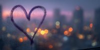 Heart shape drawn on foggy window glass with romantic city lights bokeh background at sunset creating warm atmospheric love concept.