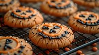 Orange frosted Halloween sugar cookies decorated with black icing smiles on cooling rack, festive homemade holiday baking with candy corn scattered around.