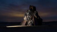 Dramatic rock formation silhouetted against twilight sky with warm ground lighting creating mystical atmosphere for landscape photography projects.