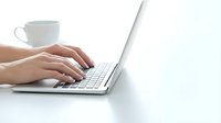 Female hands typing on modern laptop computer with white coffee cup on clean desk workspace for remote work and productivity.