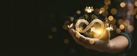 Businessman hand holding glowing infinity symbol with golden light effects and floating business icons representing endless possibilities and growth.