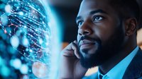 African American businessman analyzing digital data visualization while on phone call, illuminated by futuristic blue holographic display showing network connections.