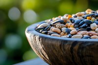 Colorful dried beans and legumes in rustic wooden bowl with natural green bokeh background, showcasing variety of pulses for healthy cooking.