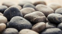 Smooth river stones with water droplets in natural earth tones creating zen spa atmosphere for meditation and wellness design projects.