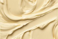 Creamy vanilla frosting texture with smooth swirls and waves, rich buttery surface showing delicate folds and glossy peaks in soft beige tones for food photography.