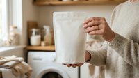 Person in beige sweater holding white paper bag in modern kitchen with wooden shelves and natural light, suitable for eco-friendly, sustainable living, and home organization concepts.